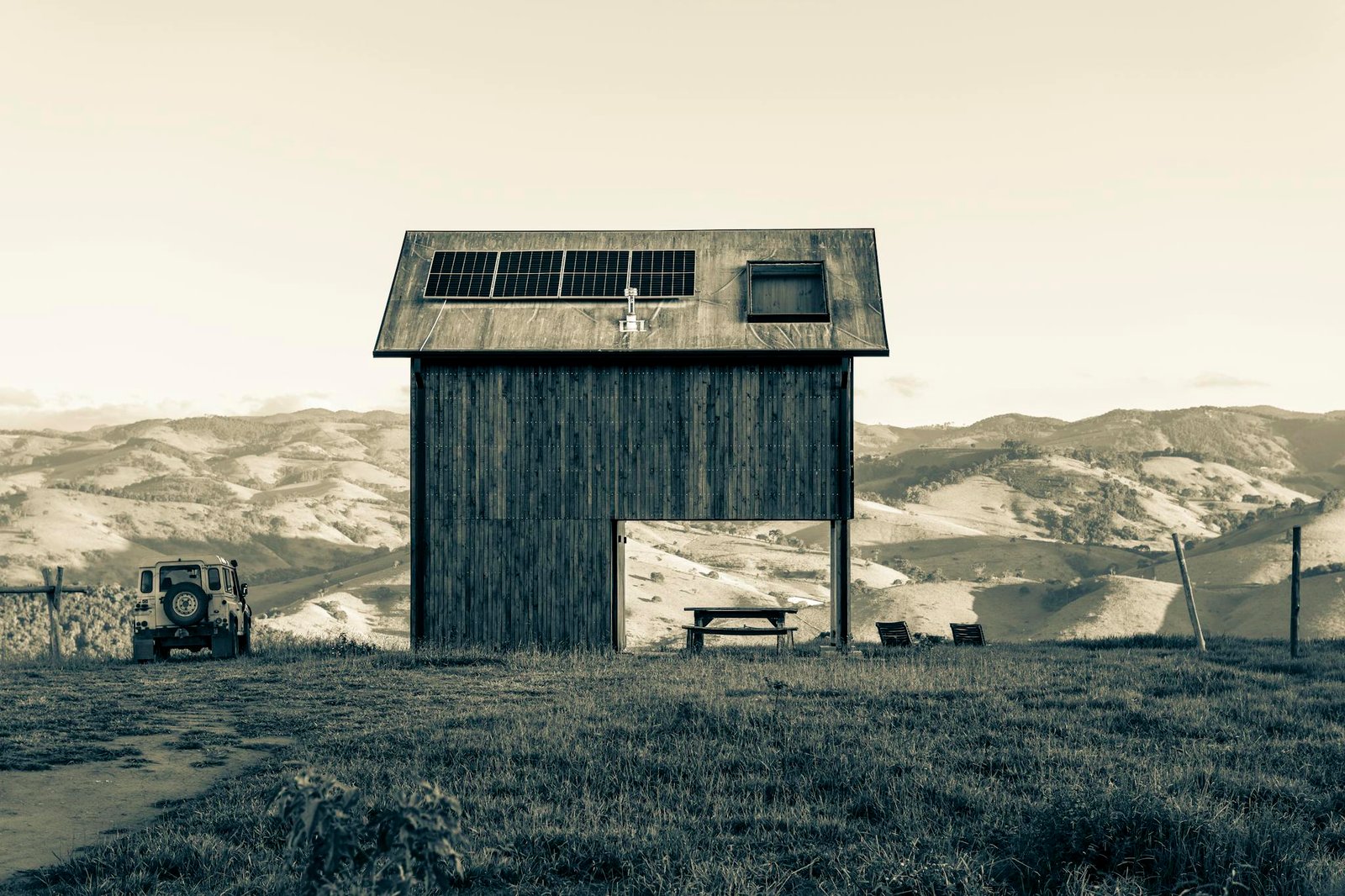 A rustic barn with solar panels, set against rolling hills and a vintage car. Perfect blend of technology and nature.