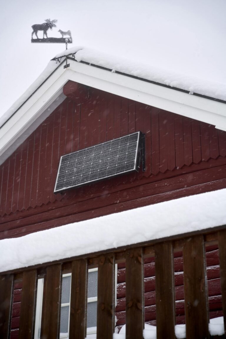 A snow-covered cabin featuring a solar panel, showcasing winter sustainability.