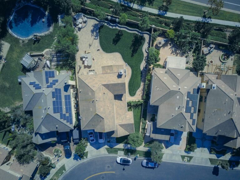 Aerial view of suburban houses featuring solar panels and green lawns, symbolizing eco-friendly living.